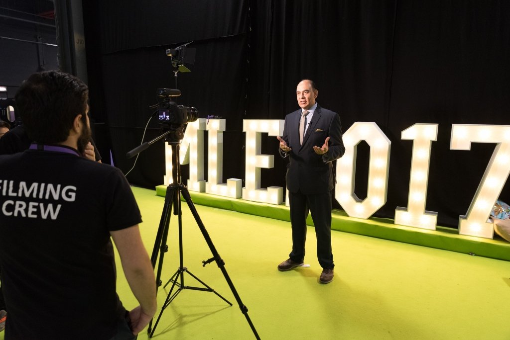 a make Direcotr being filmed infromt of light up letters at the Muslim Lifestyle Expo