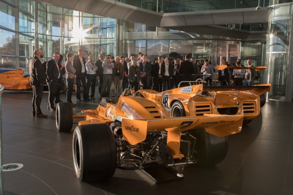 a Mclaren forula 1 car being viewed by visotrs in the showroom